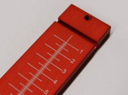 Close-up of a red metal ruler with white measurement markings ranging from 1 to 5 centimeters.